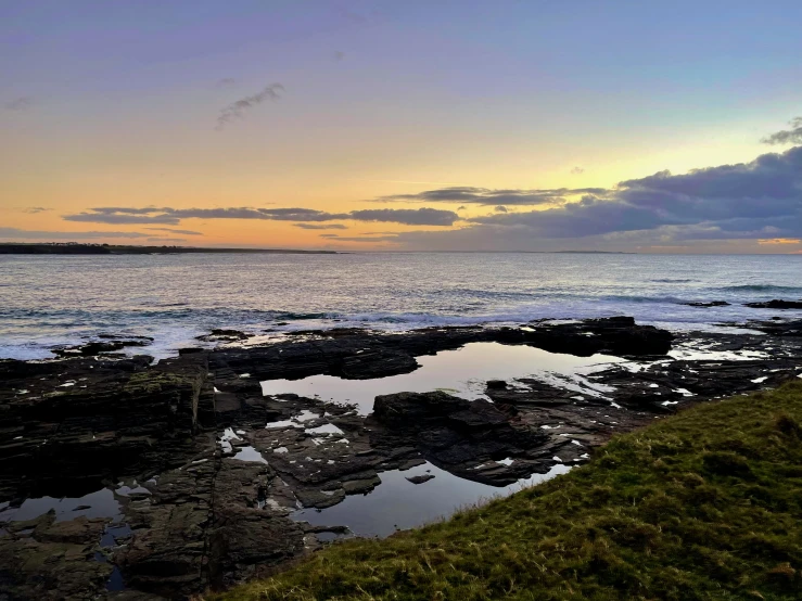 the sun is setting over a body of water with the ocean in the background