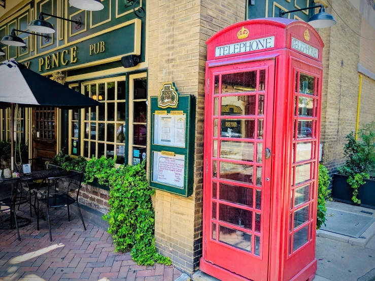 a red phone booth in front of some restaurant