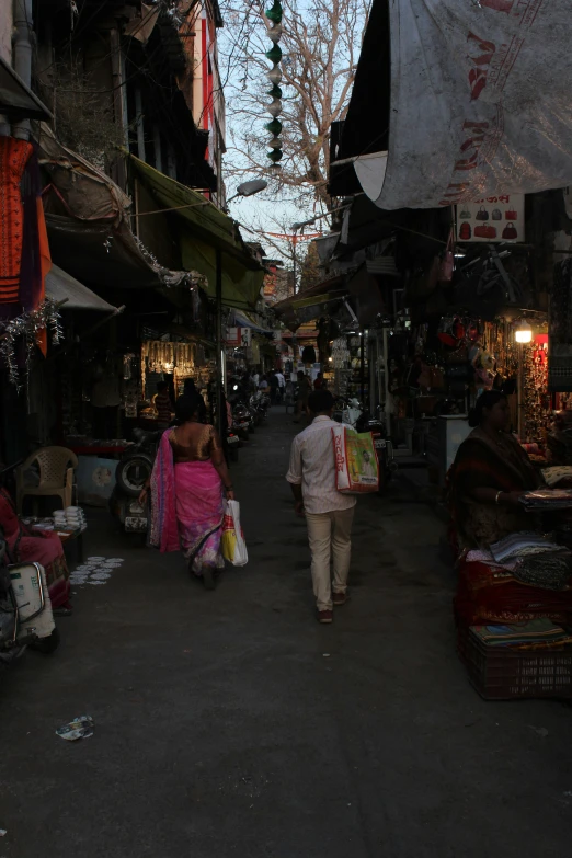 people walk through an open market on a city street