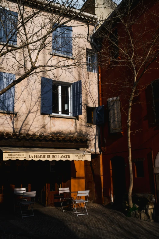 the buildings on this street are tan and brown with blue shutters