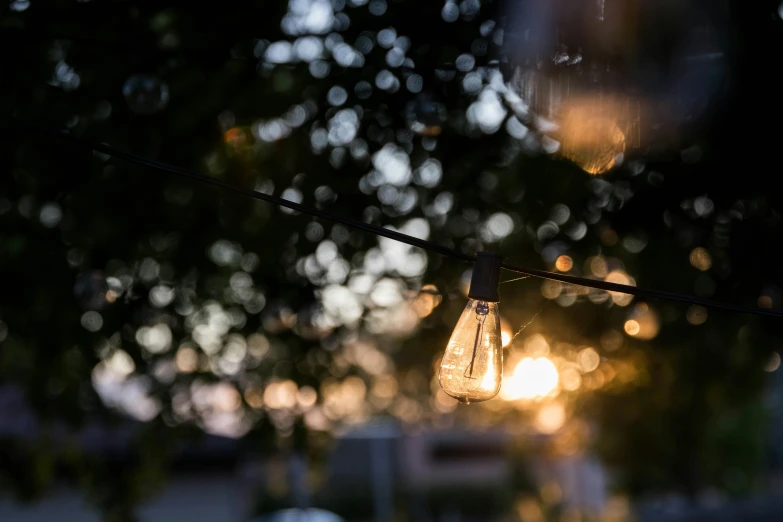 a light bulb suspended from a wire outside at night