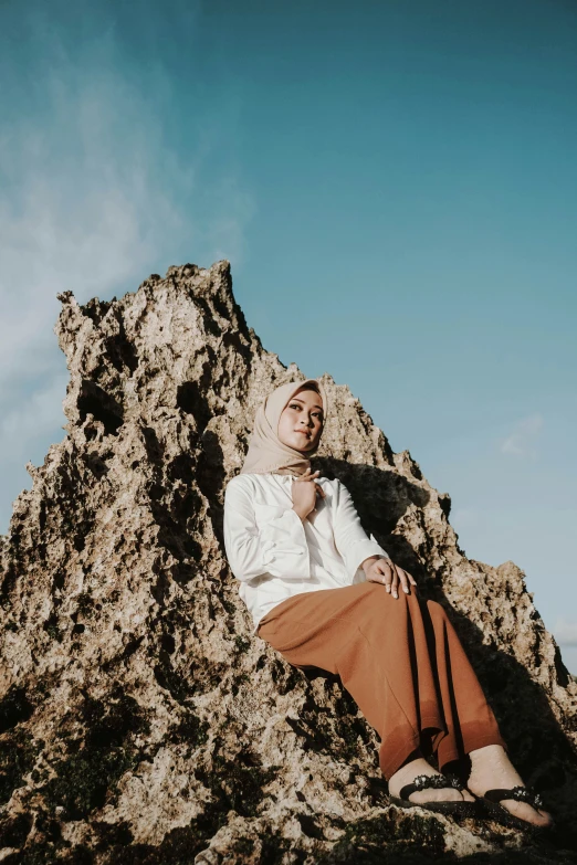 a man sits on a rock wearing a tie