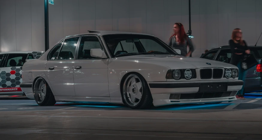 a white bmw is parked in front of two other cars