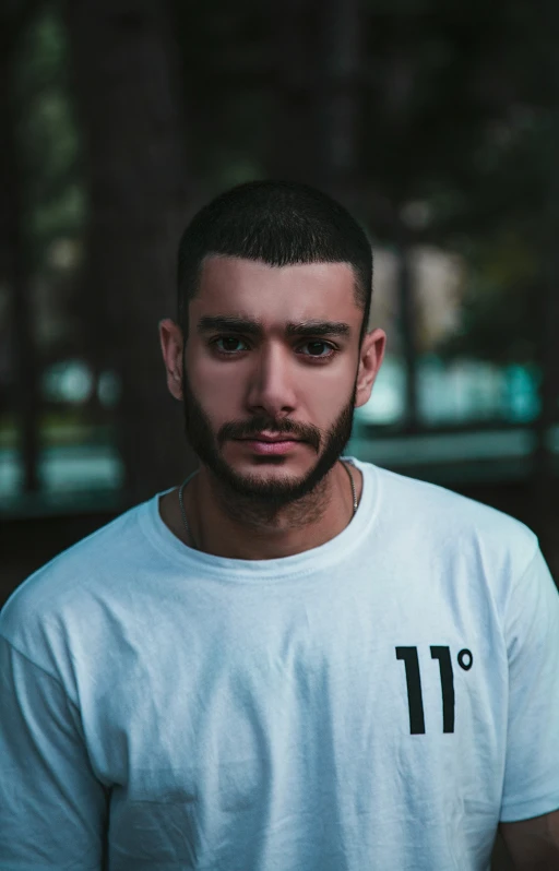 man with beard looking at camera while wearing a t - shirt