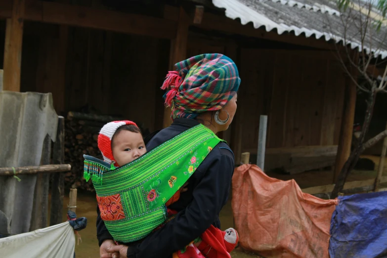 two women hold a small baby in their sling