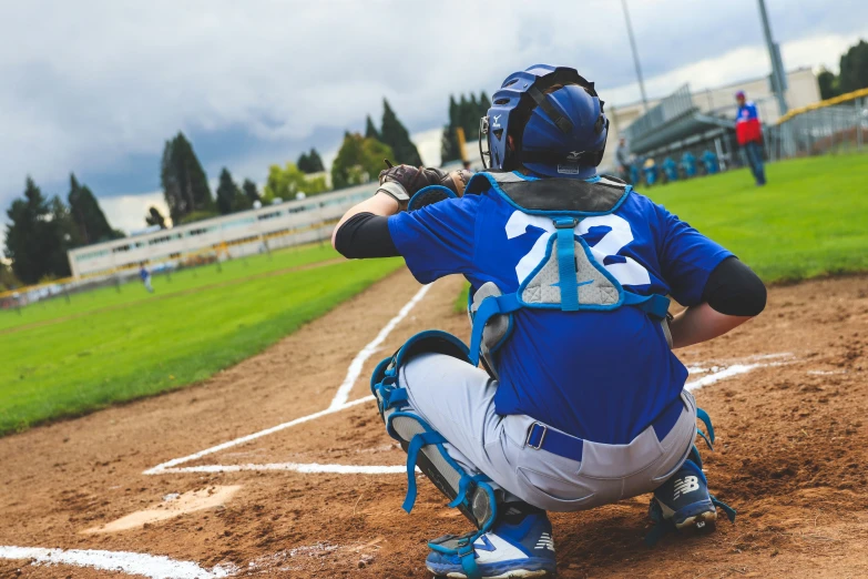 a baseball catcher squatting on a baseball field