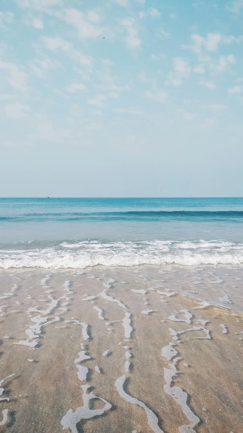 a person is walking across the sand near water