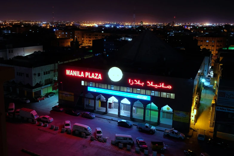 a night view of a building, parking lot and cars in front