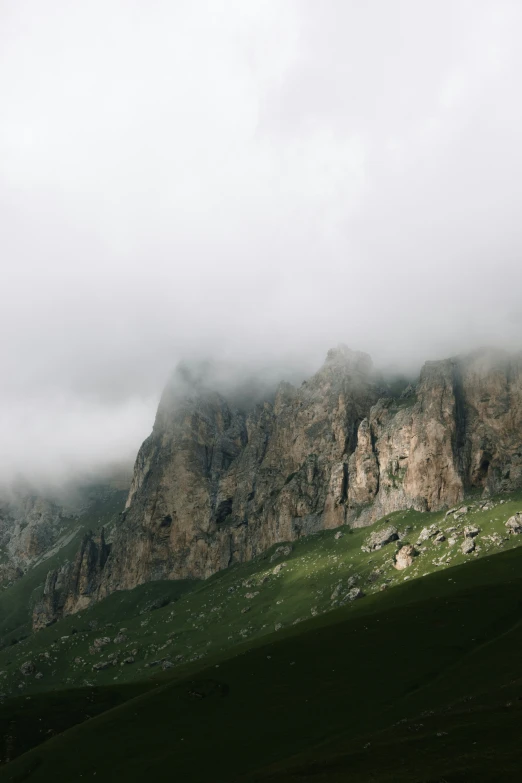 clouds hovering over some very tall rocks