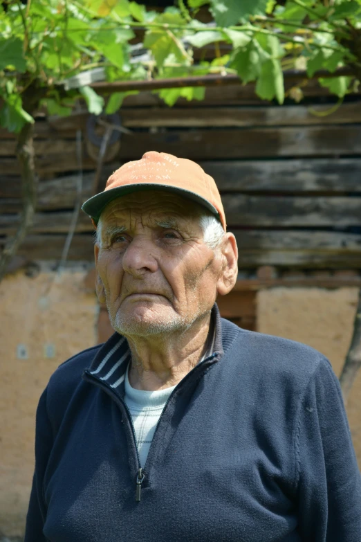 a man with a baseball cap is standing near some vines