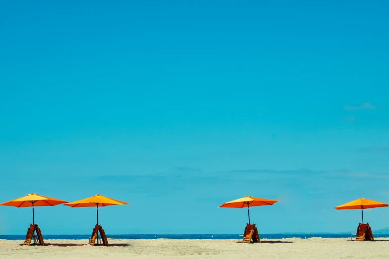 four yellow umbrellas that are next to a beach