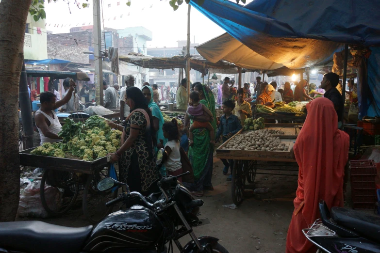 people are standing around an outdoor farmers market