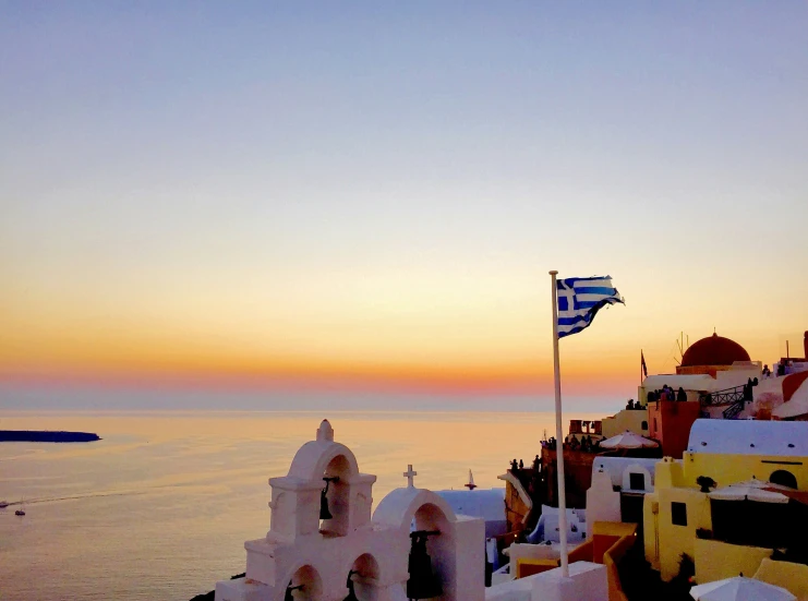 the sea shore at sunrise with a flag waving on top