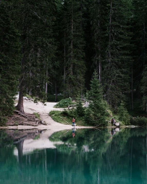 a lone figure standing in a blue lake