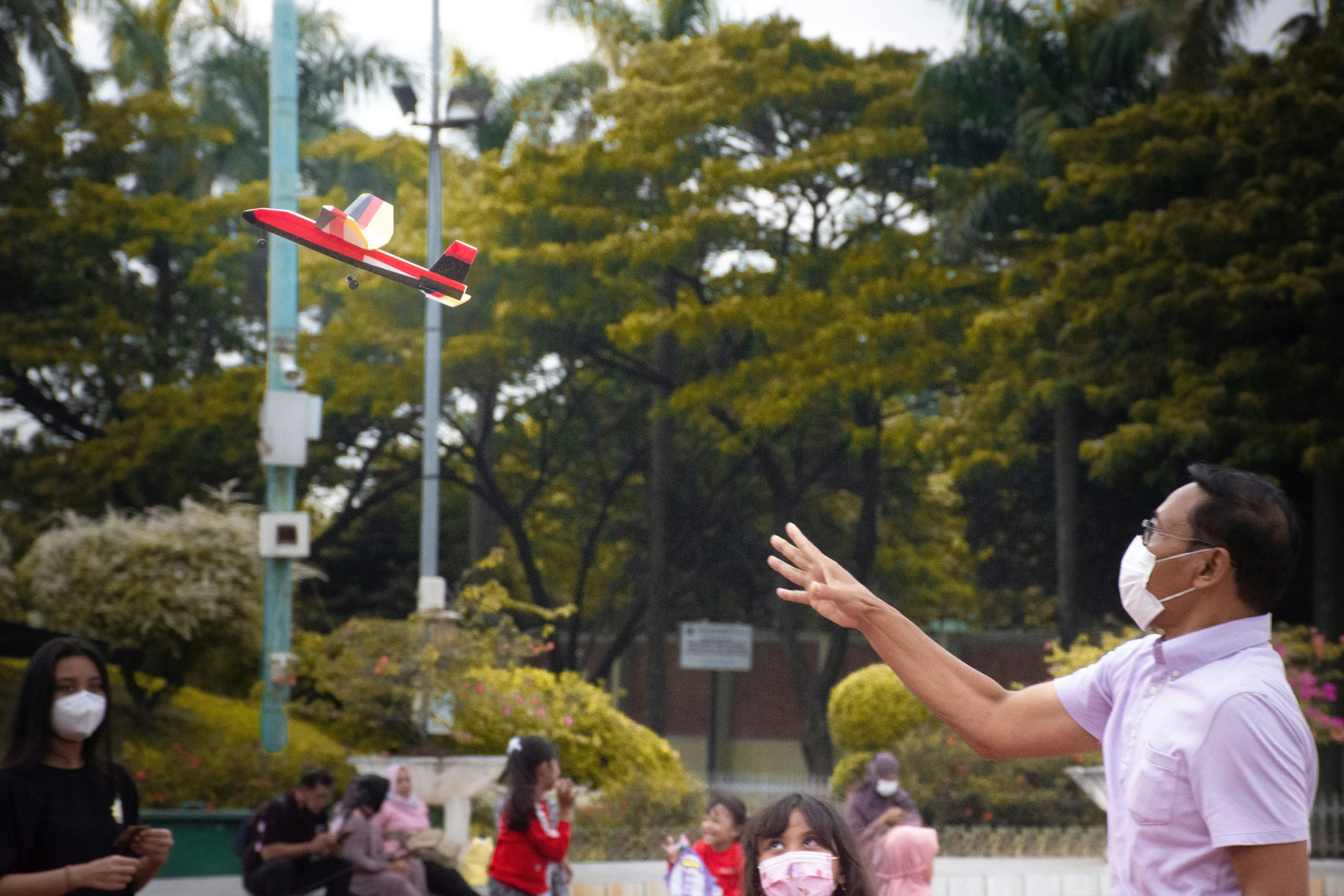 a man wearing a face mask playing with a red and white plane