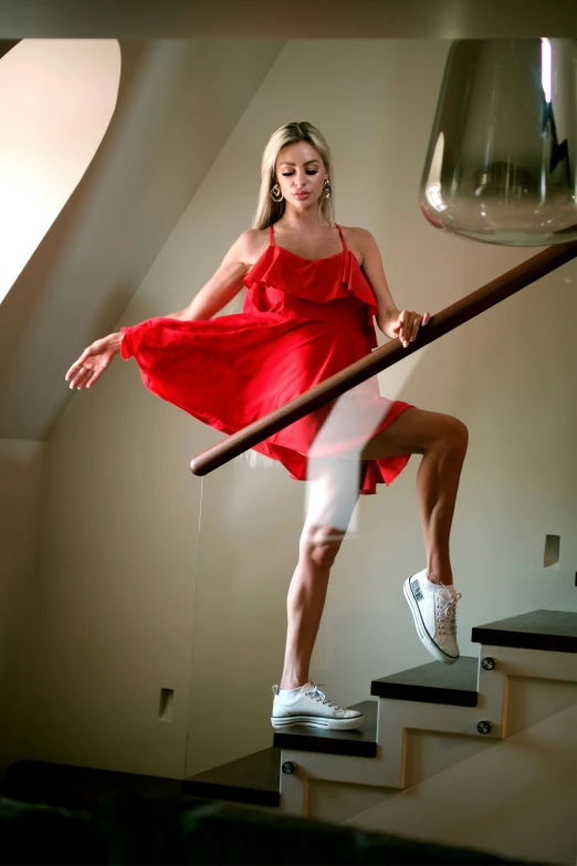 a woman wearing a red dress walking up a flight of stairs