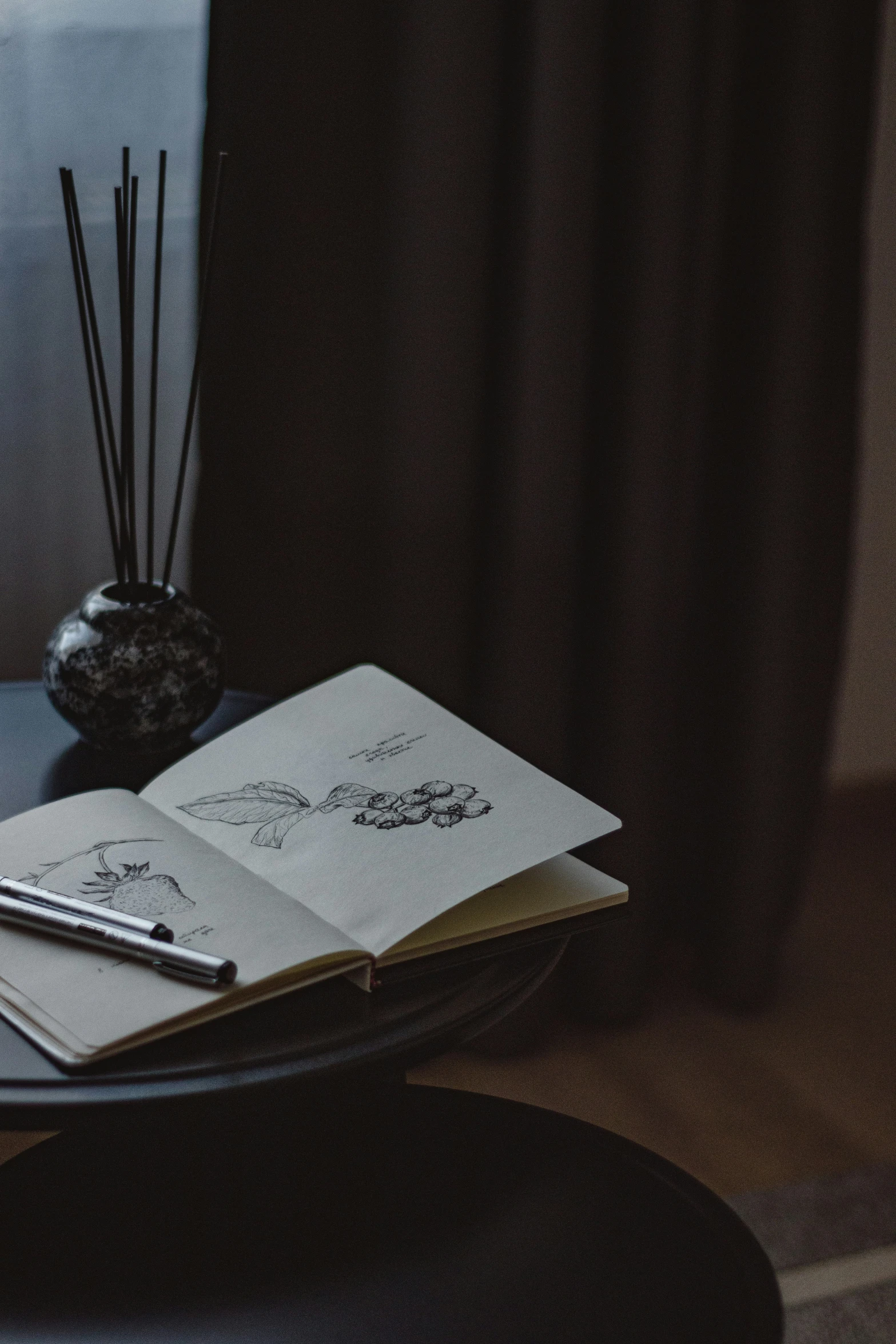 a notebook, pen and candles sit on a table