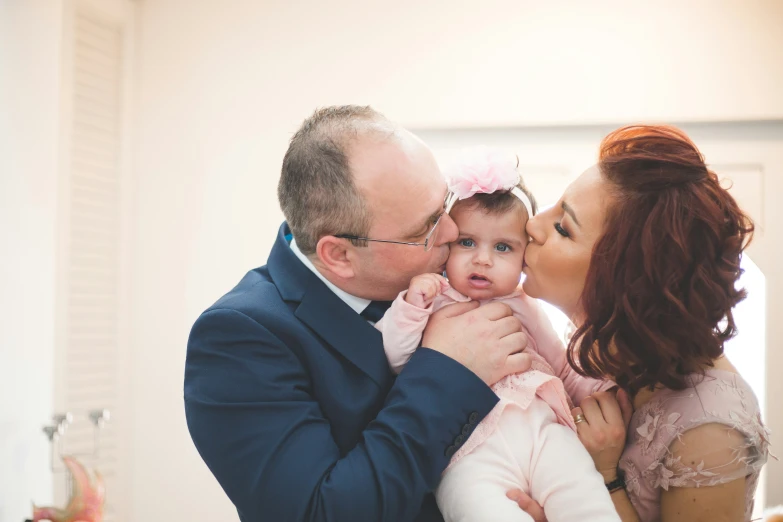 a man kissing a woman holding a baby