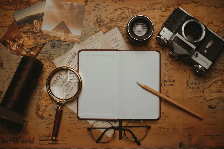 a notebook, glasses and a camera sitting on a map