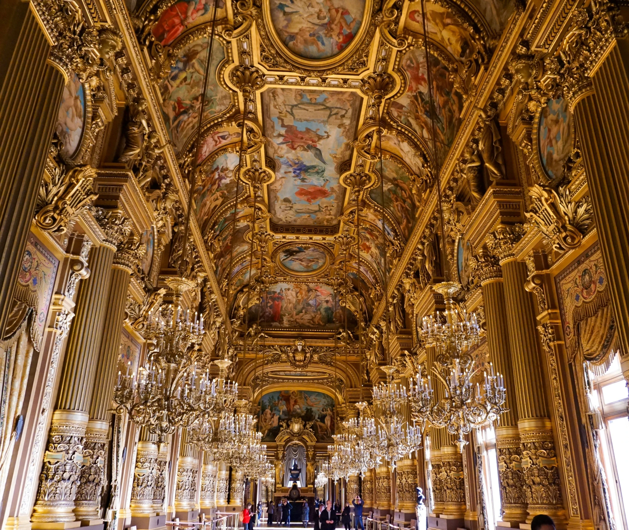 an ornate gold painted building with large chandeliers and artwork on the ceiling