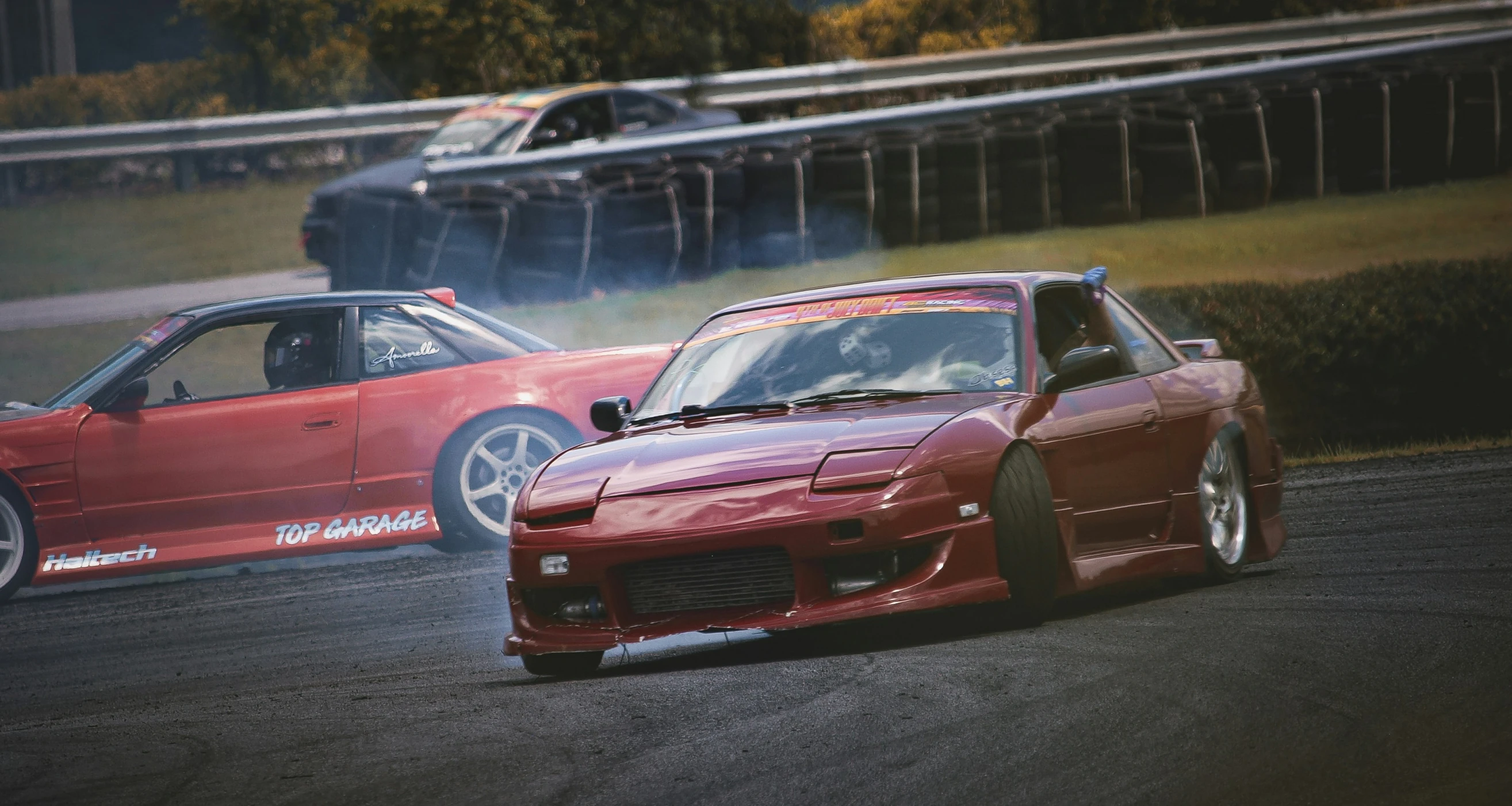 red cars racing on a track with smoke coming out of the hood