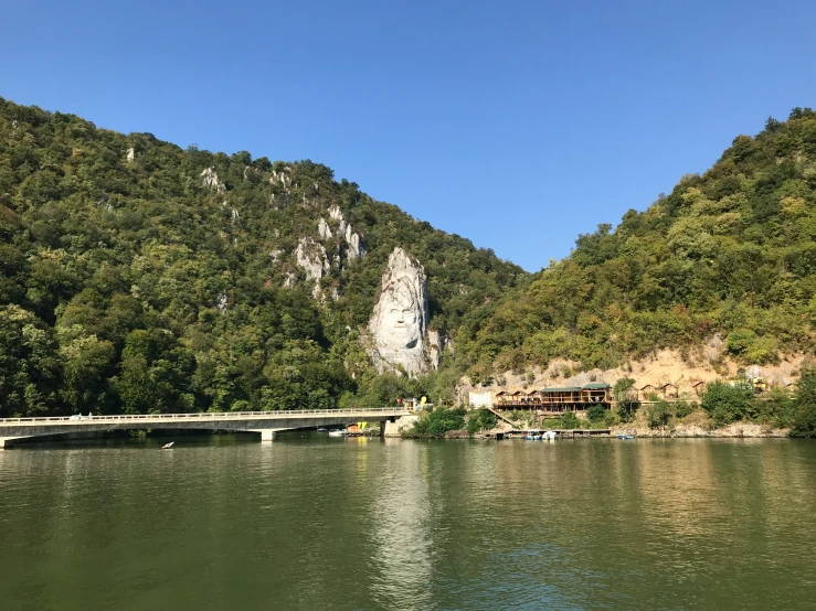 a lake with a bridge across it with people out on the side and mountains in the distance