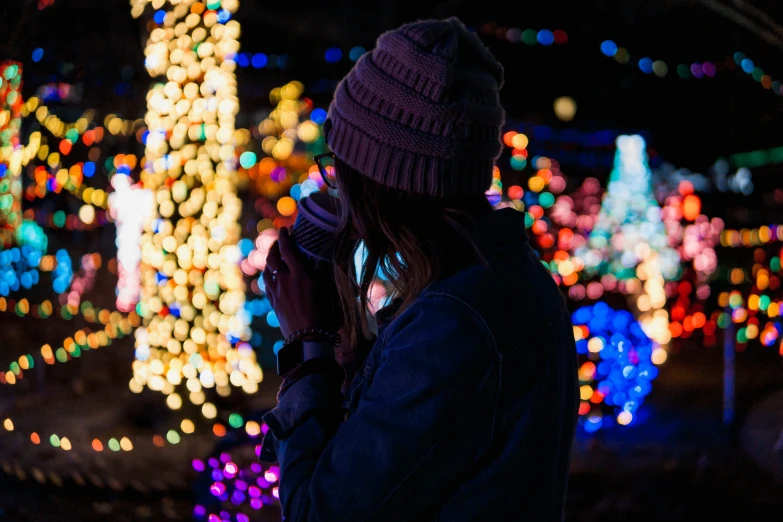 the woman is standing in front of christmas lights