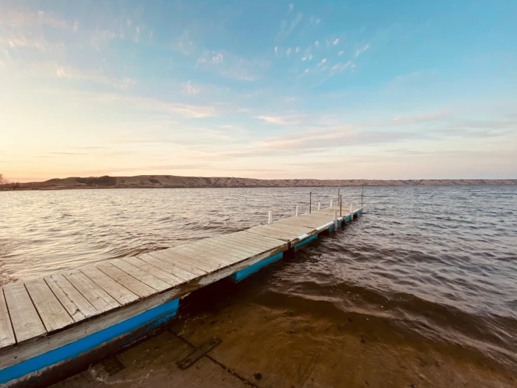 a dock leading to the shore line at sunset