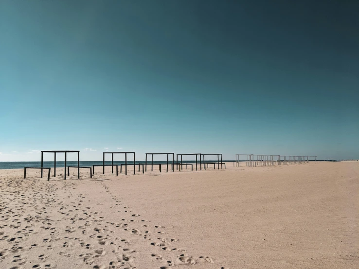 the empty beach has many square posts on it