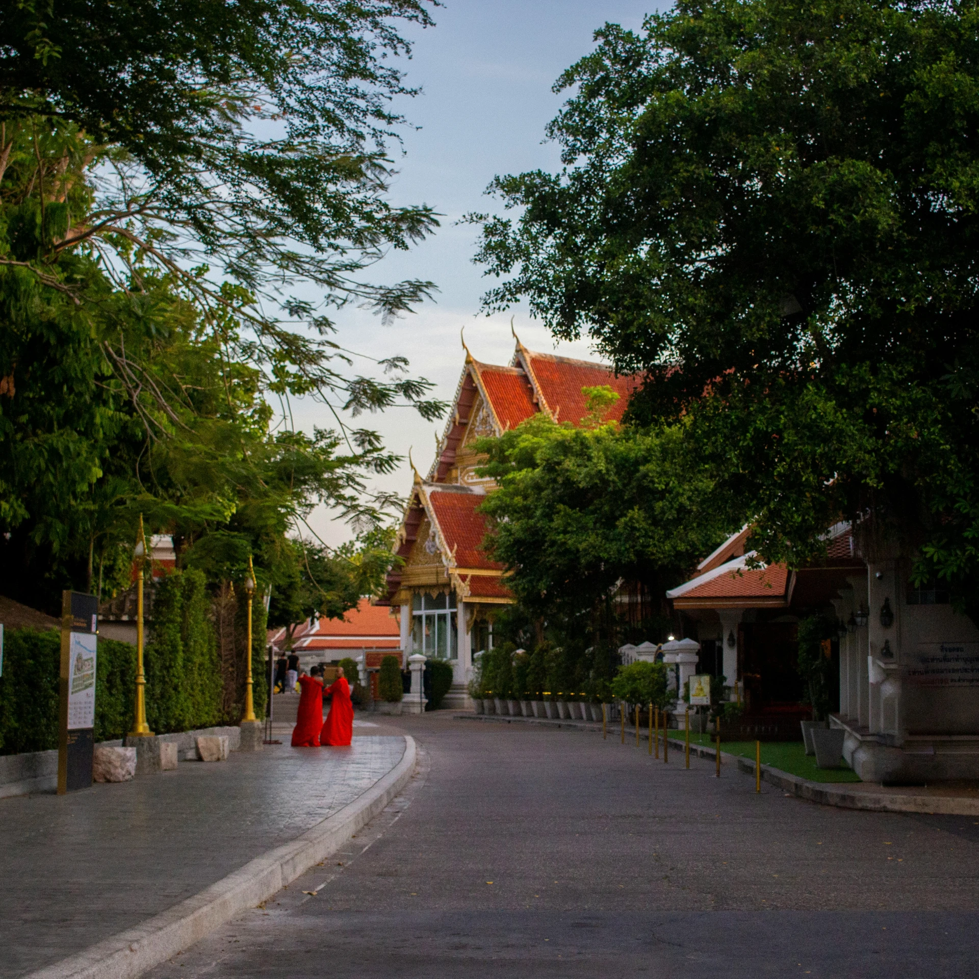 two red clothed women in orange robes walking in the street