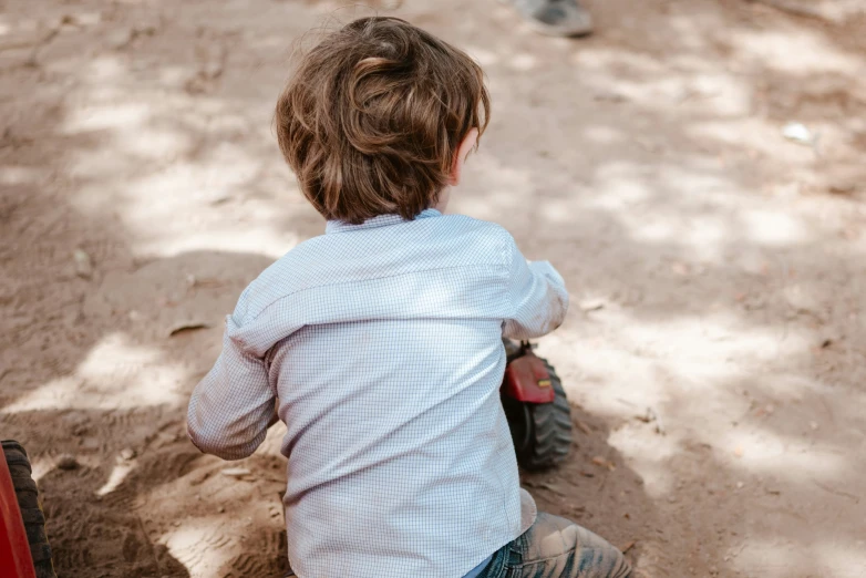 a little boy riding a motorcycle through a dirt field