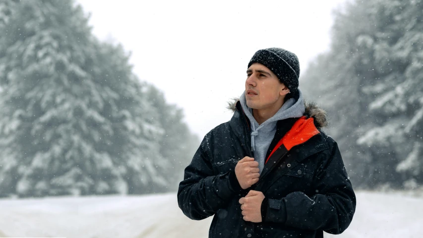 man standing in snow while wearing jacket and hat