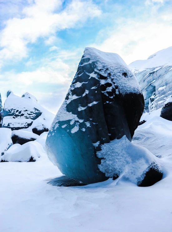 there is a large rock that has been partially buried in the snow