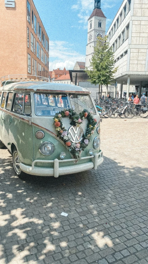 a vw van decorated with flowers and greenery in front of a building