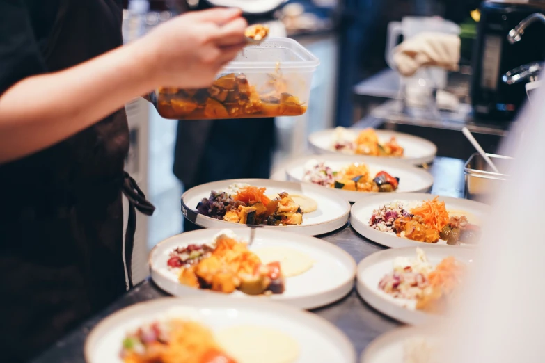 a person pours a small jug over a tray of food