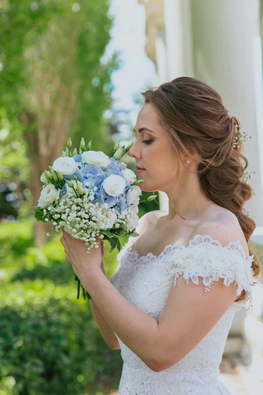 a bride holds a bouquet of flowers while looking off in the distance