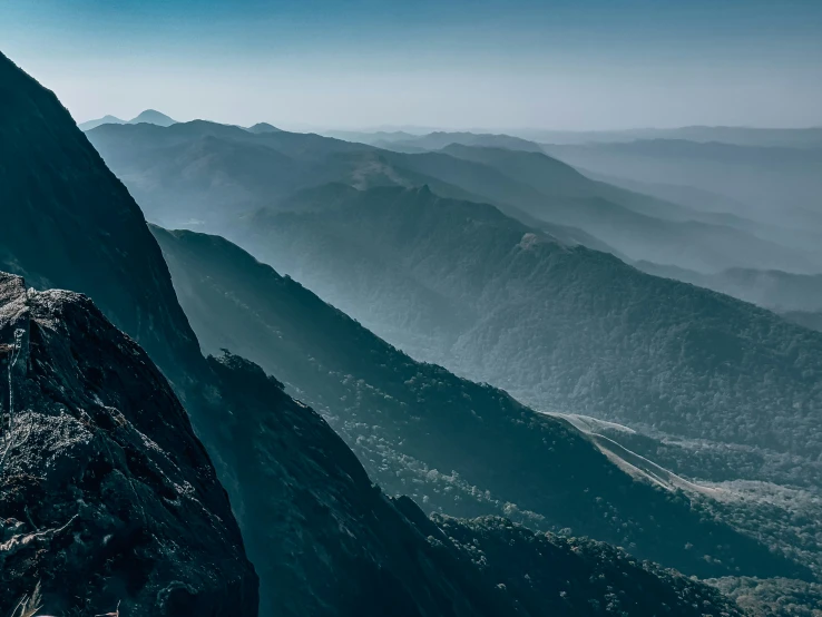 a person is sitting on the edge of a high mountain