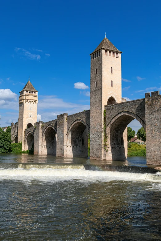 large stone bridge and arches on waterway with blue sky