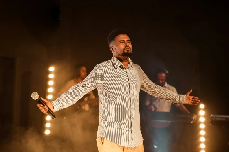 a man in a shirt holding his arms out while standing on stage