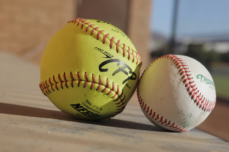 two yellow and black baseballs on a brick surface