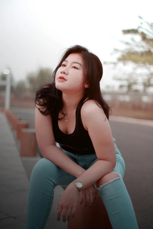 a girl wearing green pants sitting on a bench