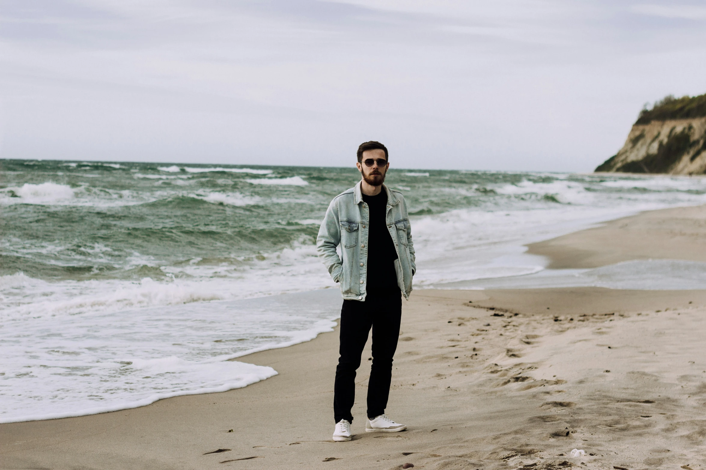 a young man standing on top of a sandy beach