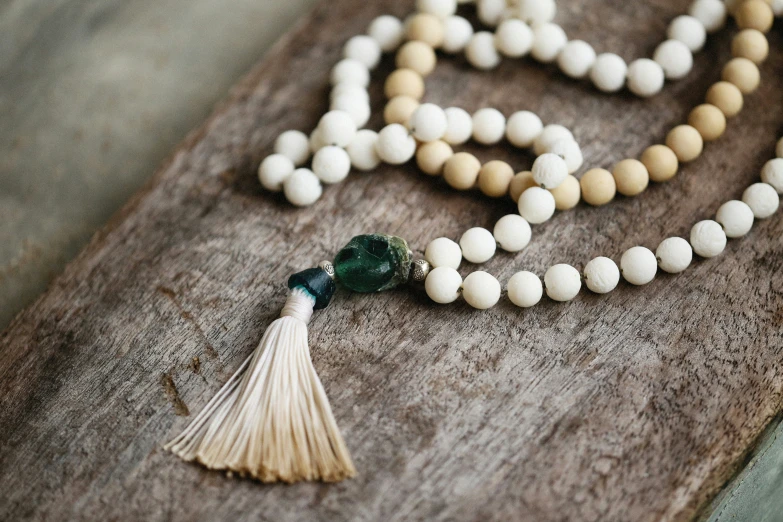 a long beads necklace and tasseled beads laying on the ground