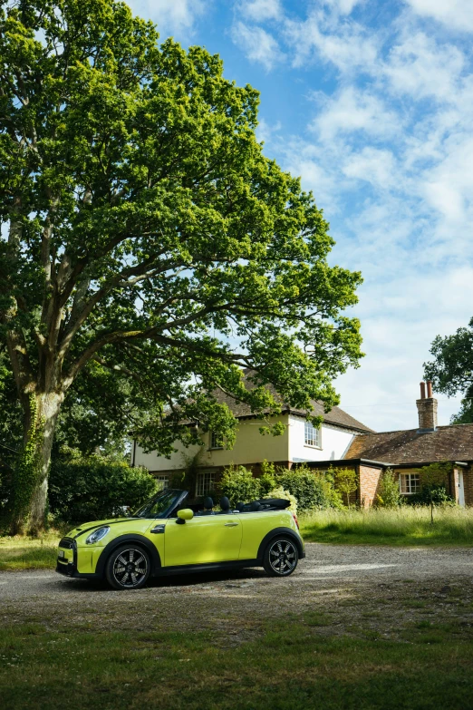 the green convertible car is parked by the trees