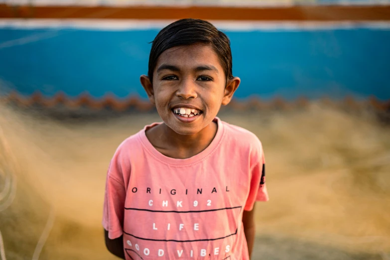 a boy standing in front of a wooden fence