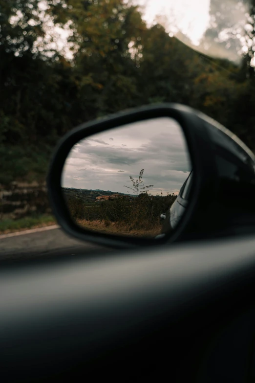 the view in side mirror of car at sky with clouds