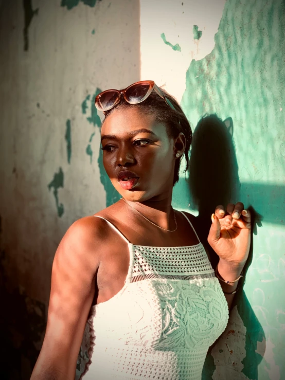 a woman with glasses on her face leaning against a wall