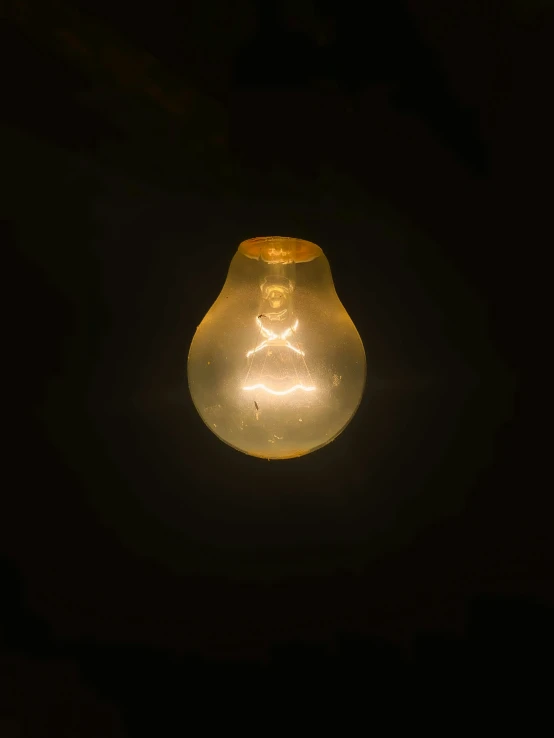 a lit light bulb with a person and a cross in the middle of it