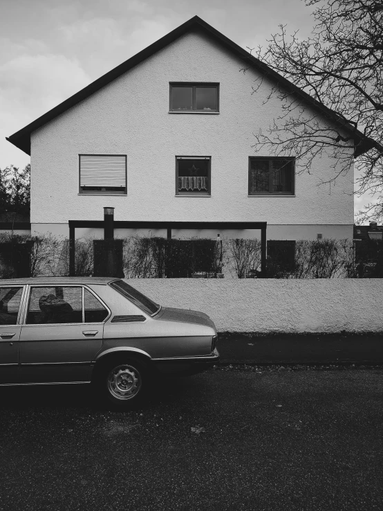 black and white po of a car parked outside a home