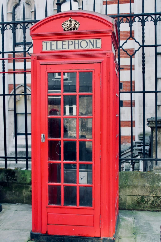 red telephone booth in front of fenced area with fencing